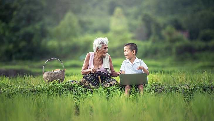 Image of old lady and little boy taking about what they see on a laptop screen
